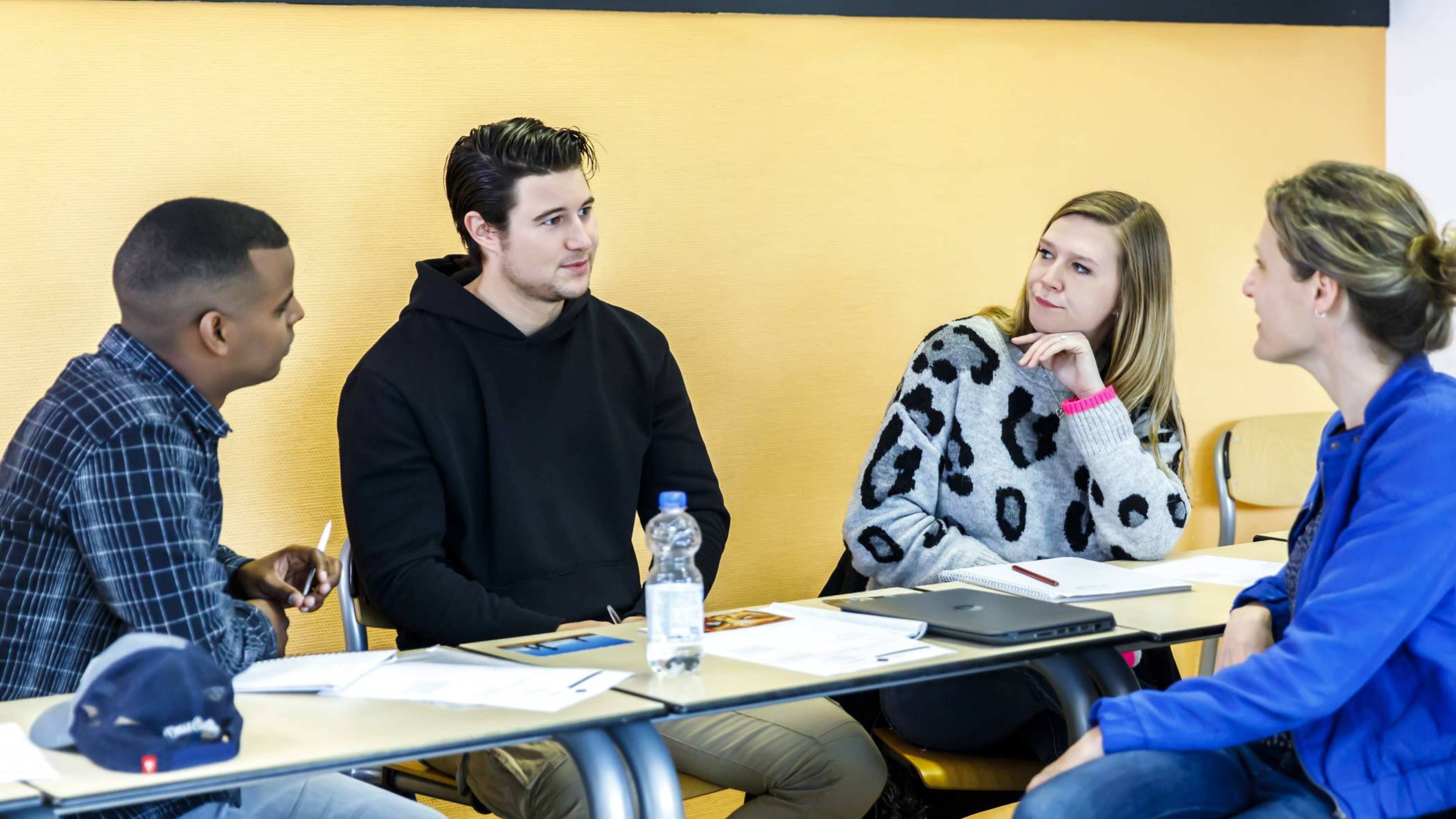 drie studenten op rij in klas met docent