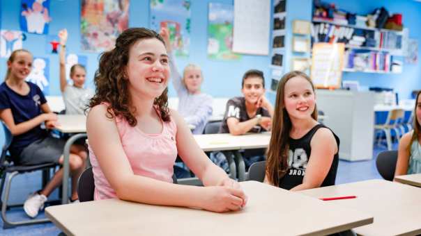 Foto van zijaanzicht van kinderen die lachend in de klas zitten.