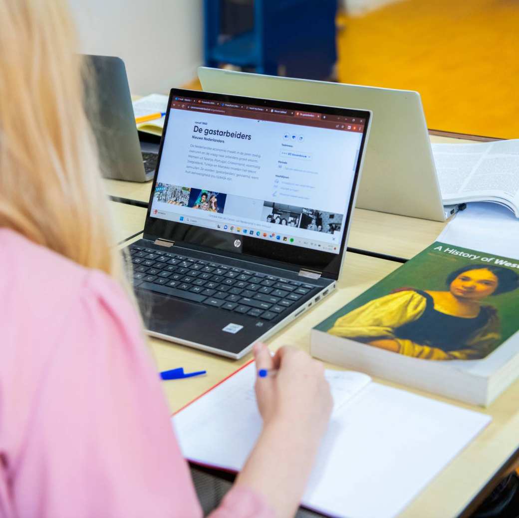 Vijf studenten spelen een kaartspel met iets te drinken erbij.