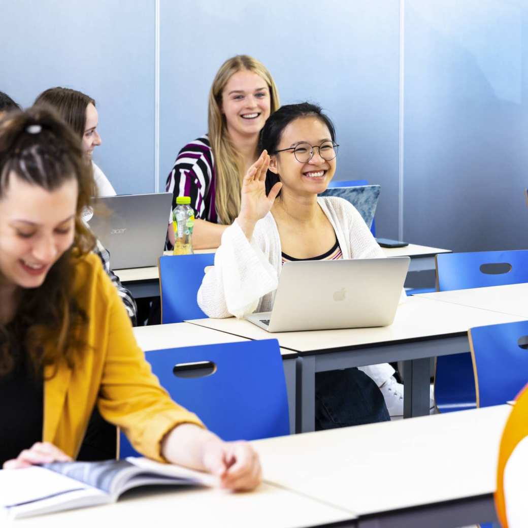 Students in a class, one student puts her hand up