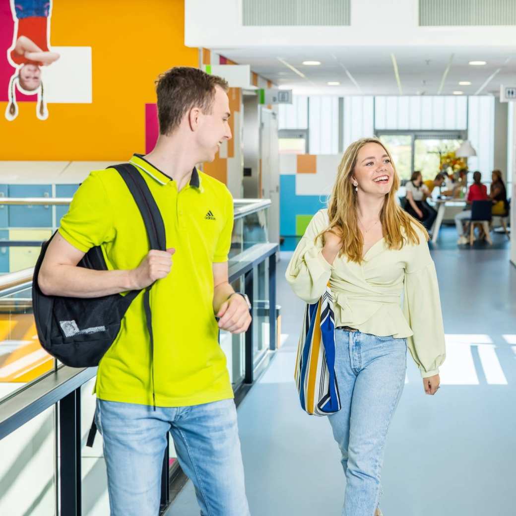 Drie studenten (2 jongen en 2 meiden) wandelend in gang K33. 