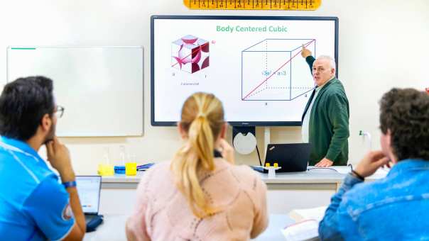 De docent geeft les aan drie studenten
