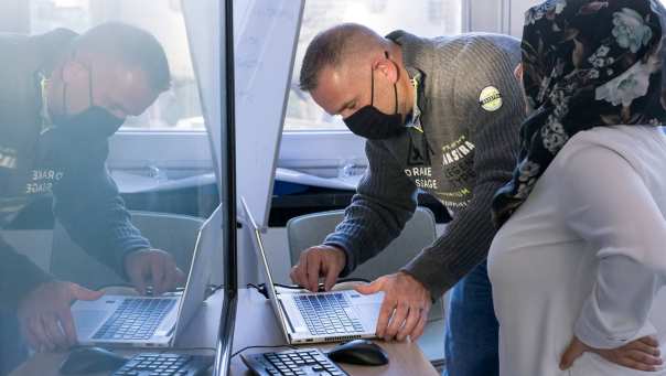 Vrouw wordt geholpen in het aansluiten van haar laptop om te presenteren voor de klas