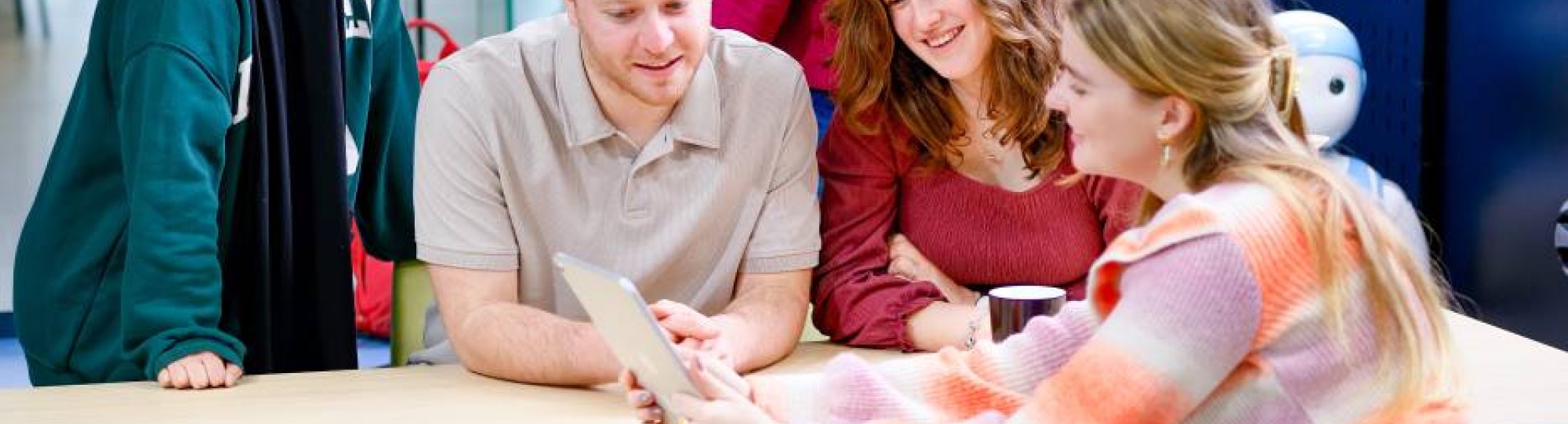 Studenten kijken lachend naar een iPad