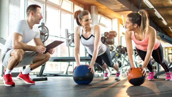 meisjes die met fitnessballen oefenen onder begeleiding van instructeur