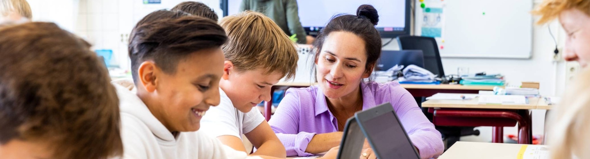 docent kijkt aan tafel bij werkende kinderen