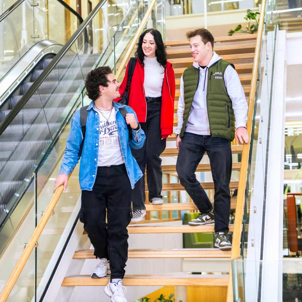 Drie studenten lopen van de trap in het I/O-gebouw