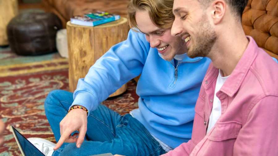 Twee studenten kijken samen op de laptop.