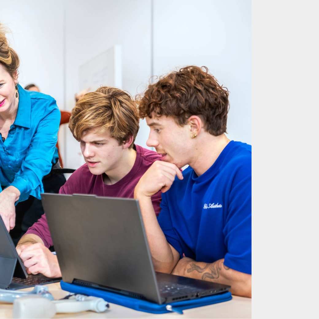 Docent legt iets uit aan twee voltijd studenten.