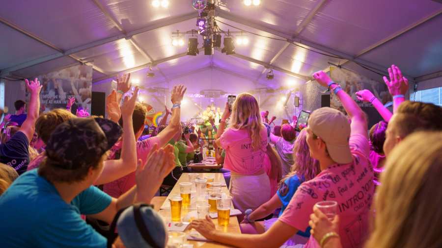 HAN-studenten aan een lange tafel met biertjes in een feesttent.