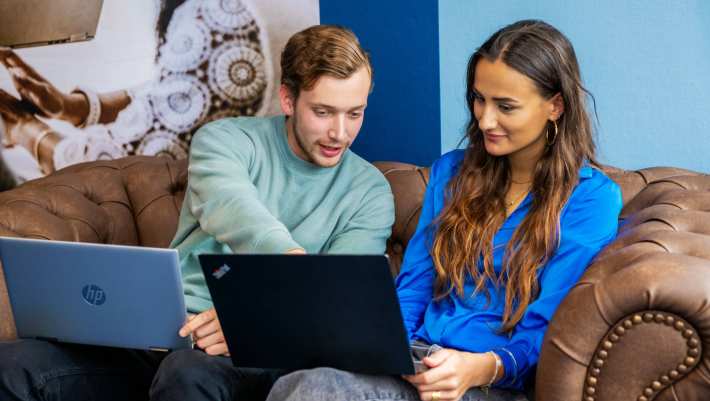 Commerciële Economie 2 studenten op bank met laptop