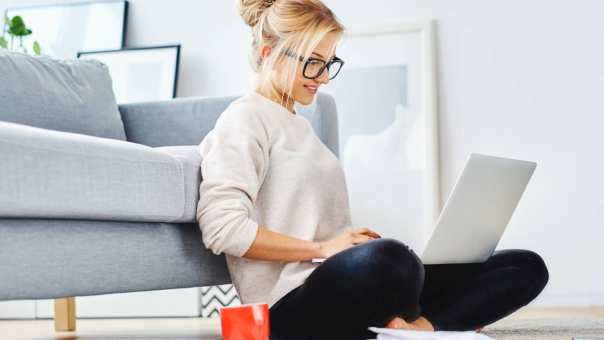 studente zit op een vloerkleed en werkt op haar laptop