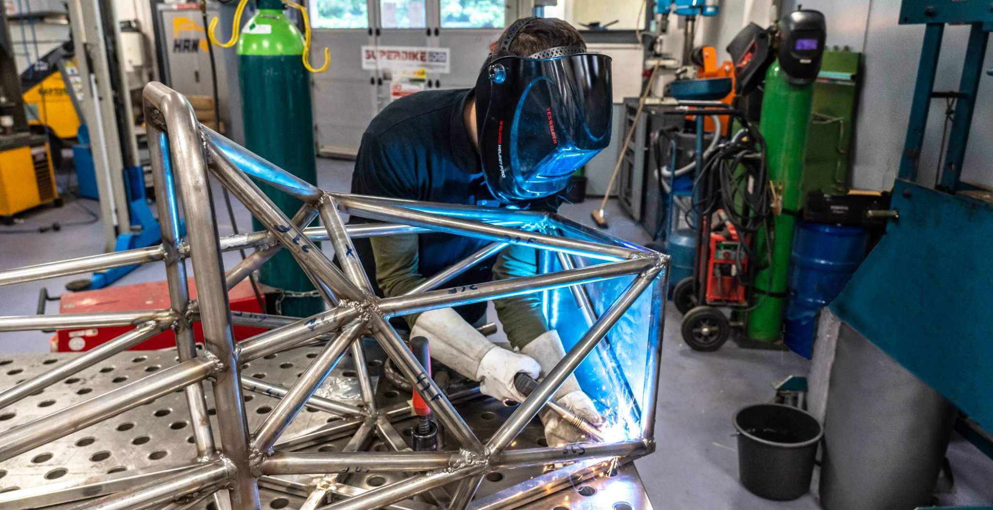 Een automotive student is een constructie aan het lassen.