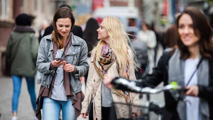 lopend door de stad, eentje met fiets, eentje met mobiel