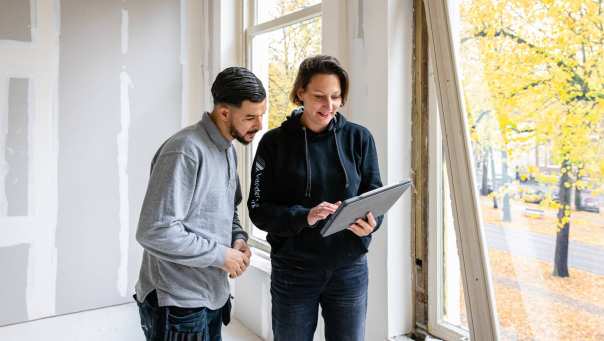 bouwkundige bespreekt bij een venster de voortgang met een medewerker