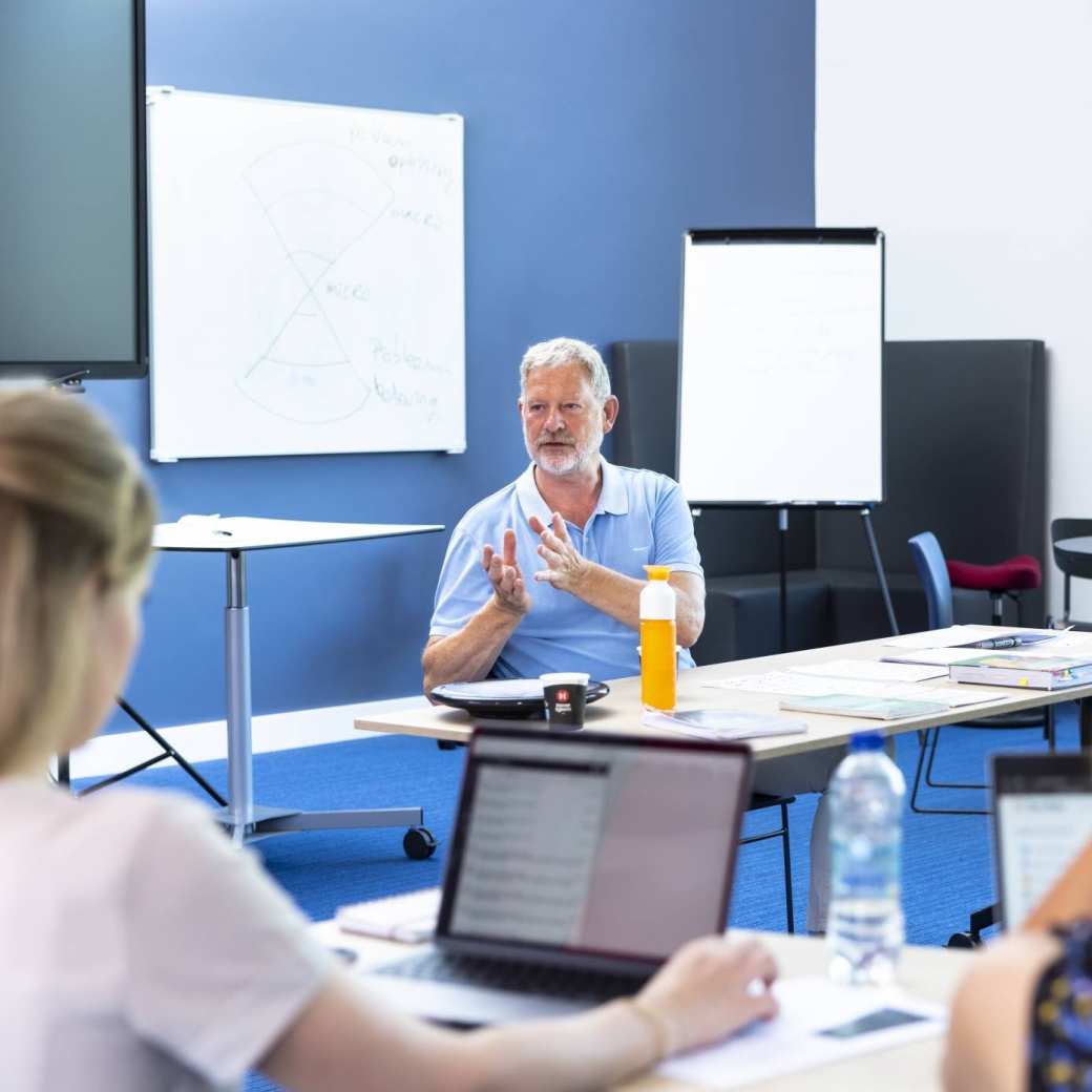 Docent geeft met handgebaren uitleg aan studenten