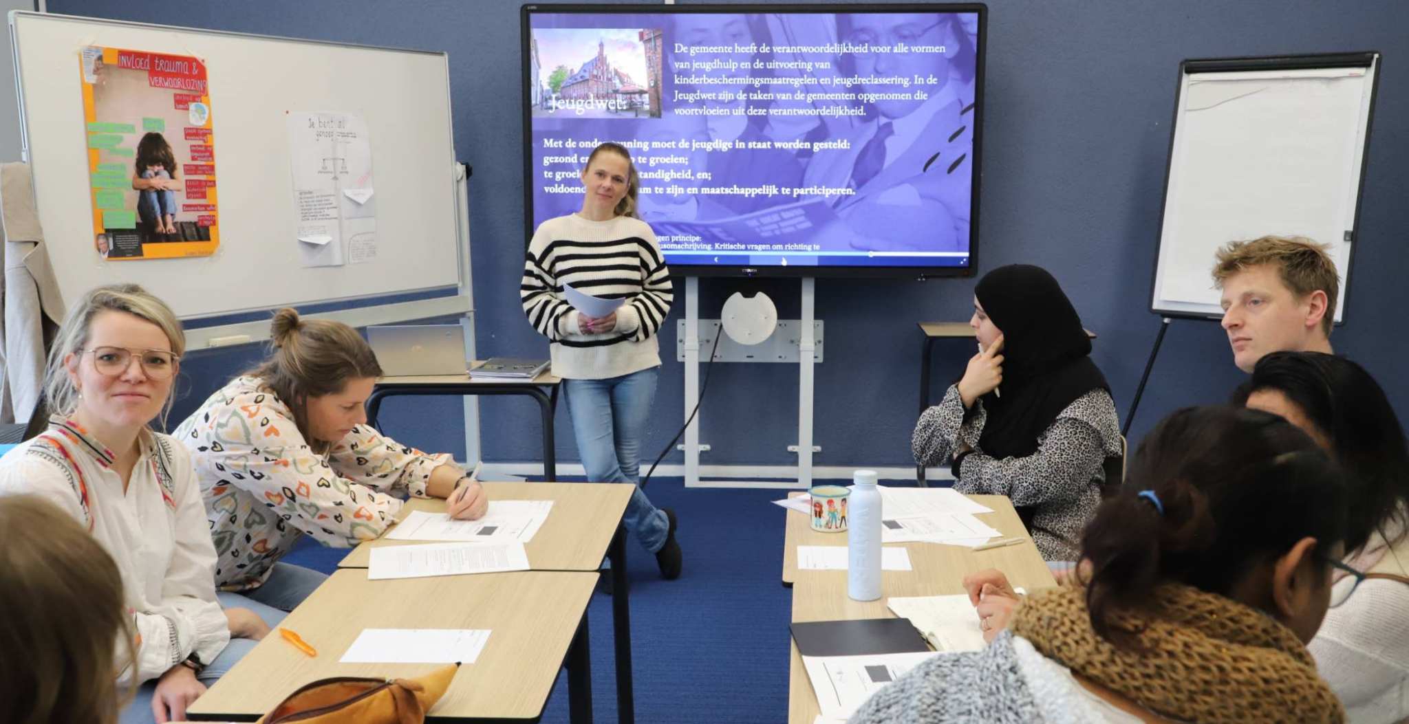 Chantine Brinks heeft blond haar en draagt dit in een staart. Ze draagt een witte trui met zwarte strepen. Ze staat vooraan de klas met achter haar het digibord, een whitebord en een flpover. Voor haar zitten medestudenten en docenten te werken aan haar opdracht