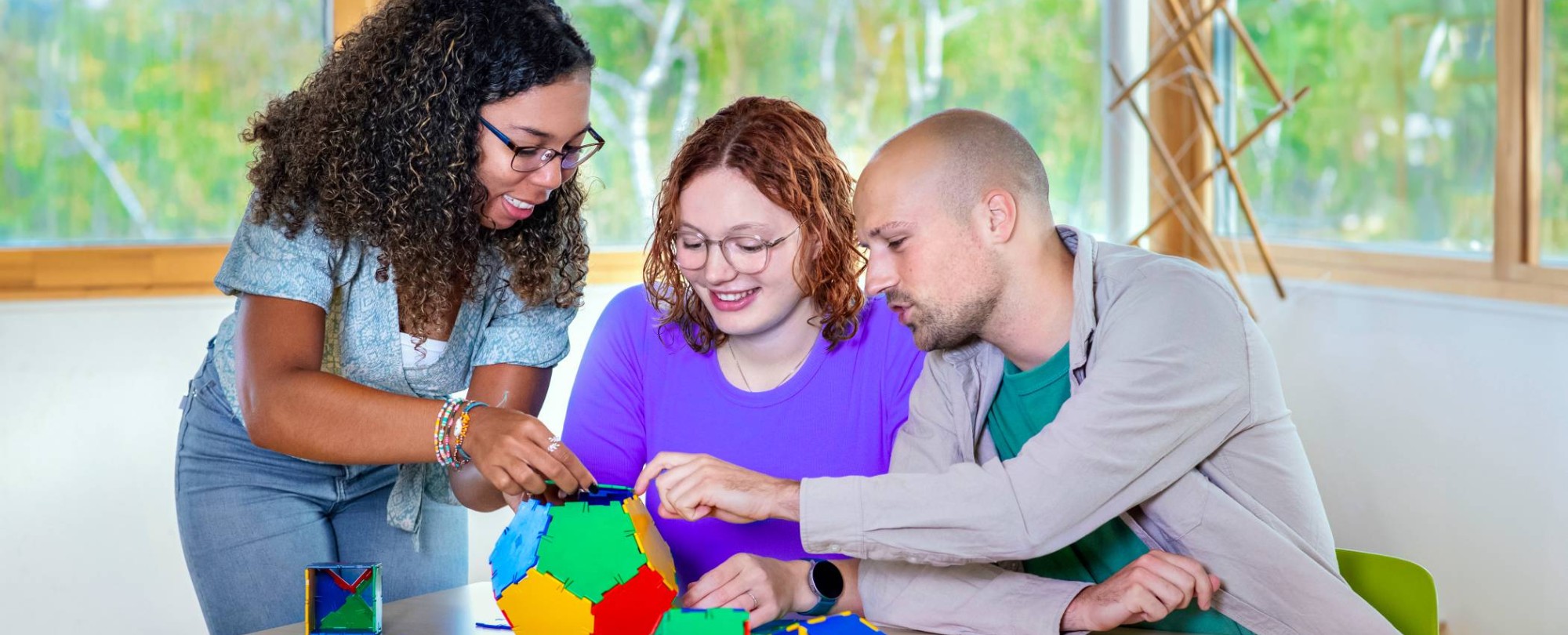 Twee studenten maken in een klaslokaal een papieren ster met allemaal verschillende kleuren.