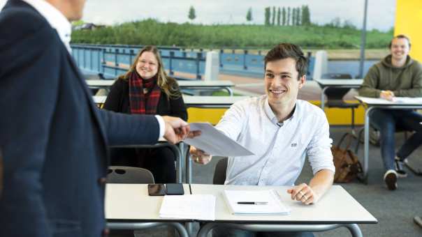 docent bram steennis geeft lesmateriaal aan cursist