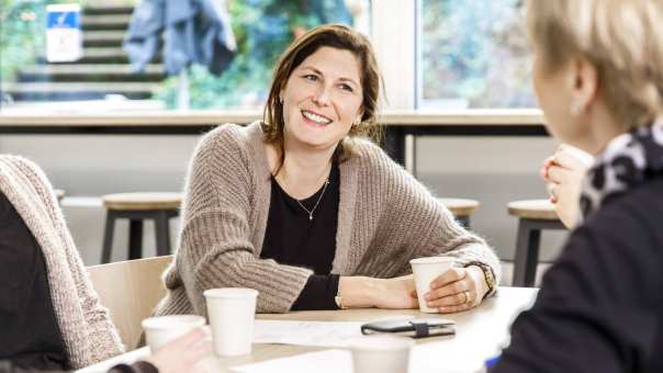 vrouw luistert met koffiebeker in hand