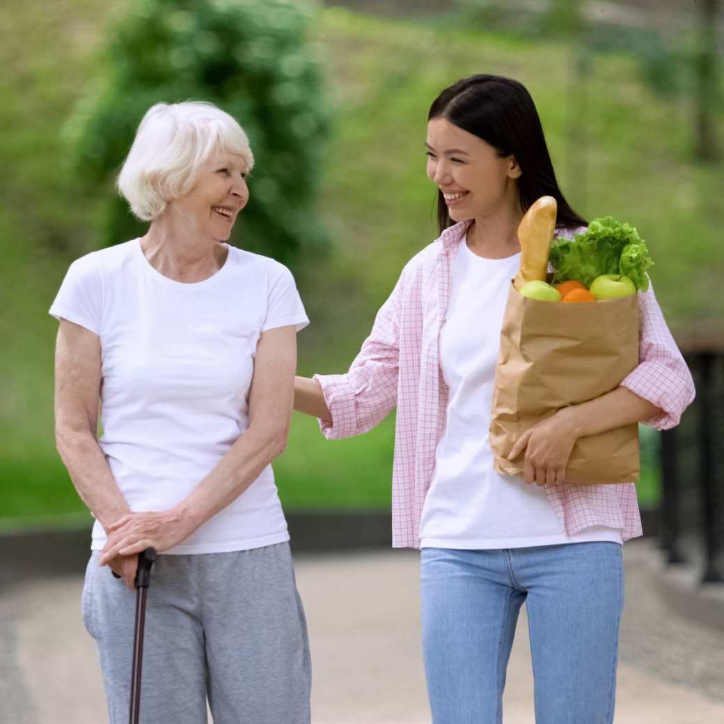 oude vrouw met stok met jonge vrouw met boodschappen in park