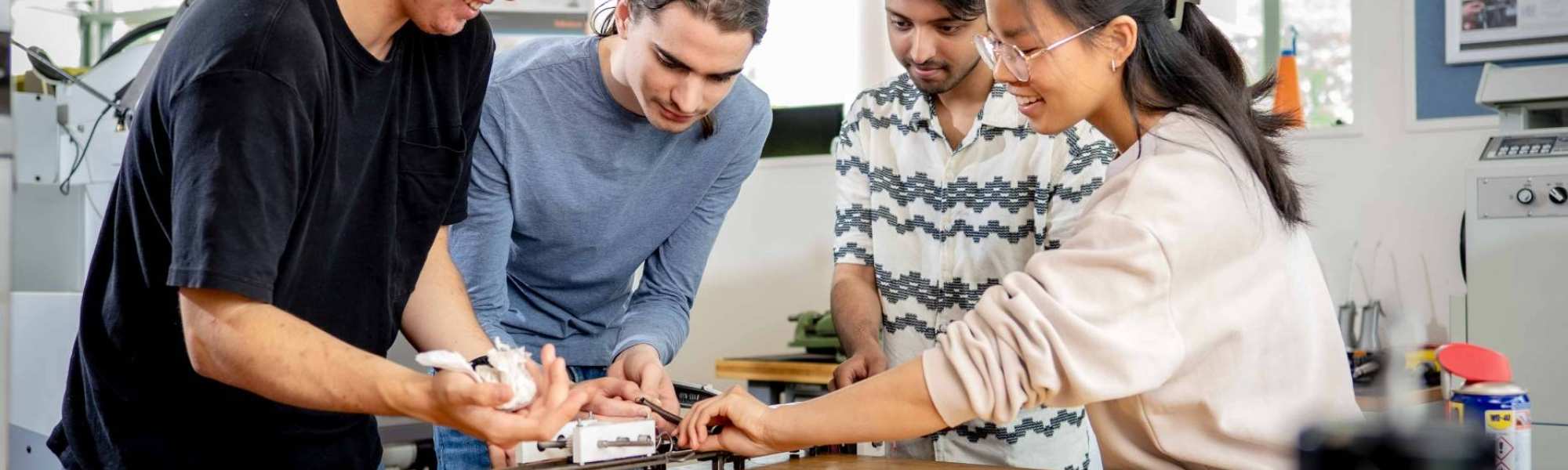 Studenten werktuigbouwkunde moeten samenwerken bij het op spanning brengen van een veer.