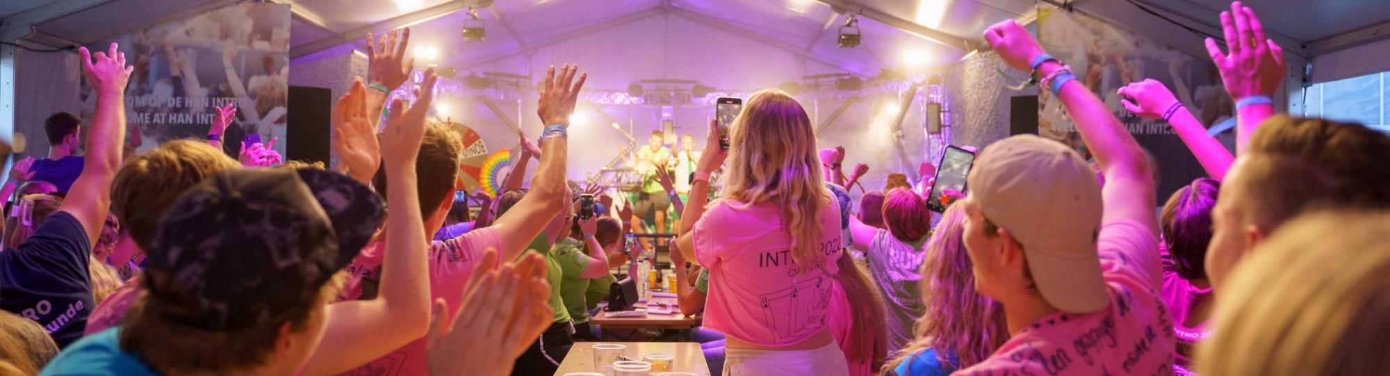 HAN-studenten aan een lange tafel met biertjes in een feesttent.