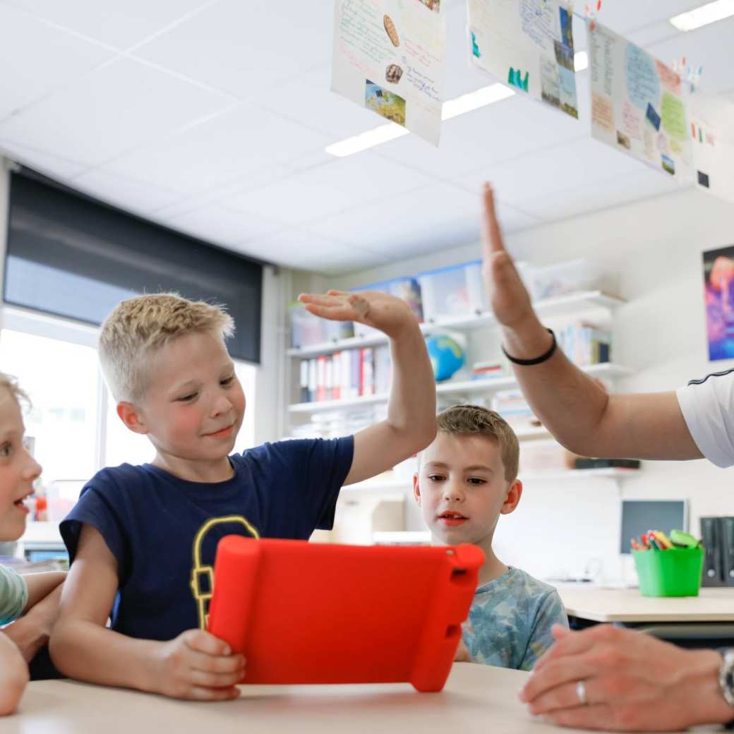 Kinderen met meester achter Ipad