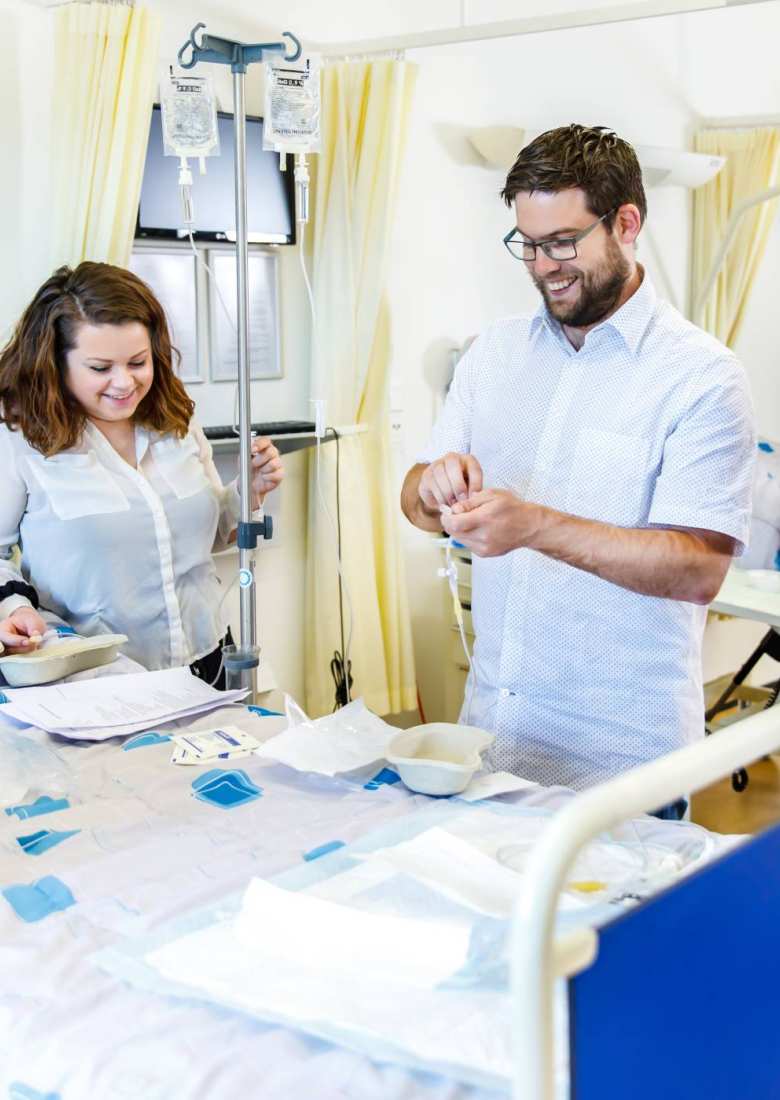 docent lachend met studenten om ziekenhuisbed