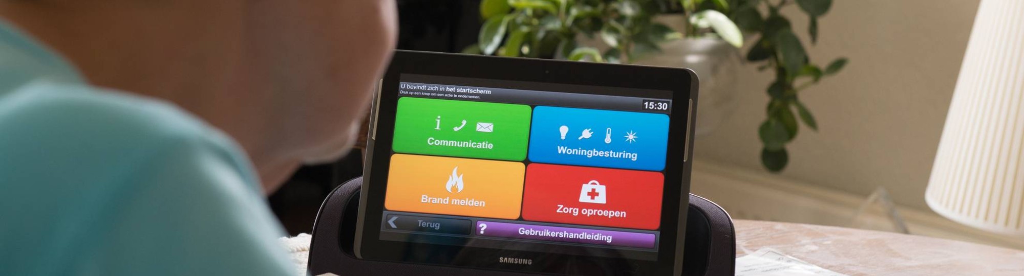 dame gebruikt een tablet met een woningcommunicatiesysteem waardoor ze langer zelfstandig kan blijven wonen