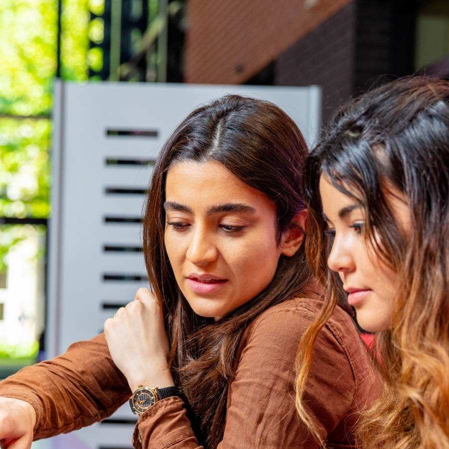 2 bachelor studenten overleggen bij een laptop op de campus.