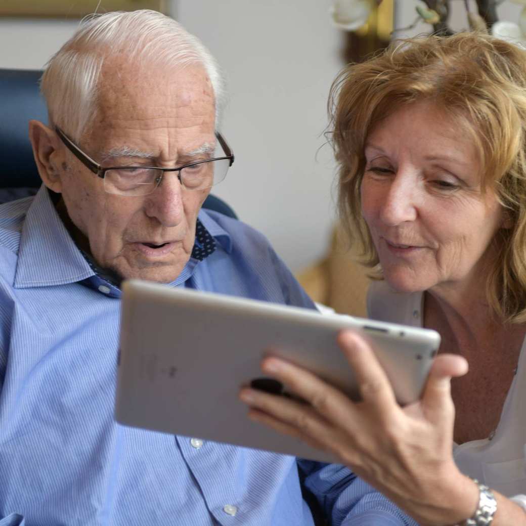 toont fotoâs op een tablet aan een bewoner van het verpleeghuis