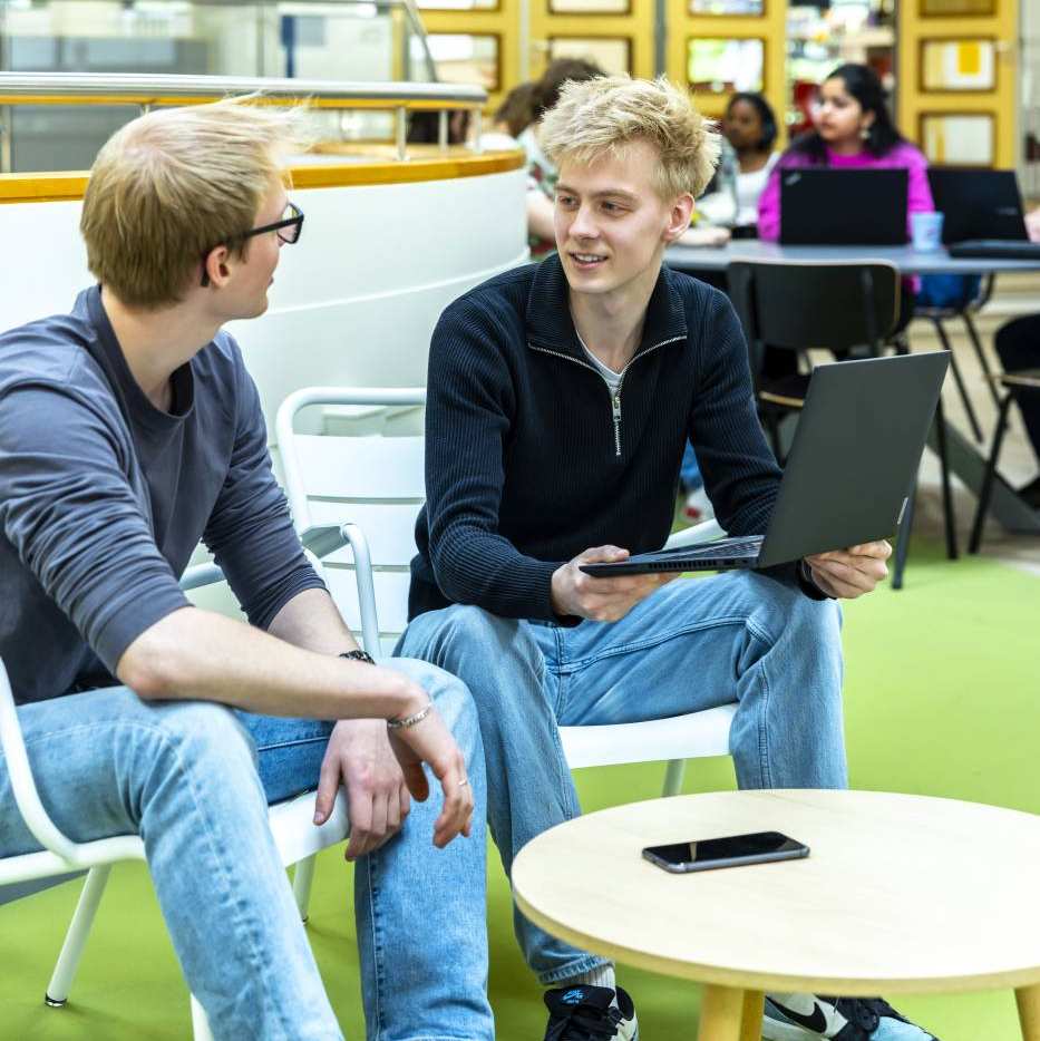 Twee jongens van de hbo-ict opleiding zijn in gesprek met laptop in de hand.