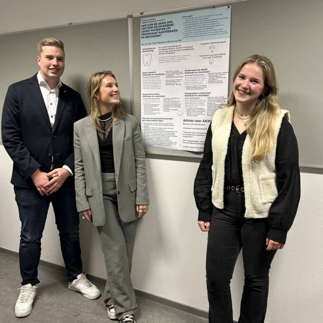 drie studenten presenteren hun onderzoeksposter