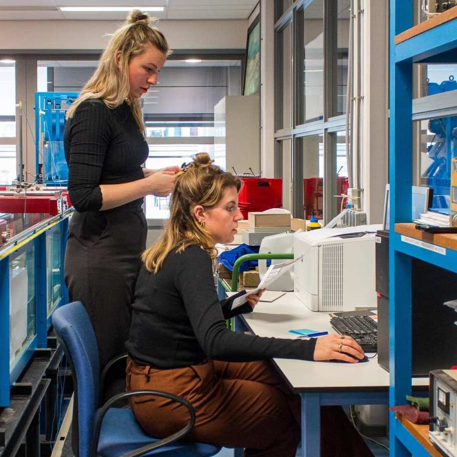 Nienke Maas en Brechtje Kraaijvanger doen een proef in het waterlab met het model van een woonboot