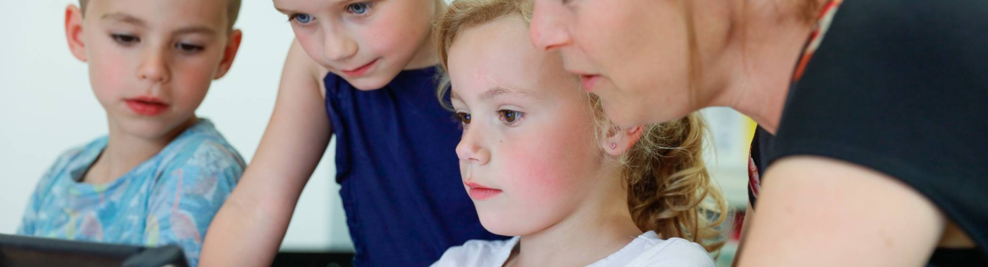 Kinderen met juf achter Ipad