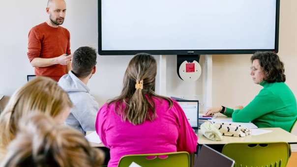 Studenten krijgen les in een lokaal. 