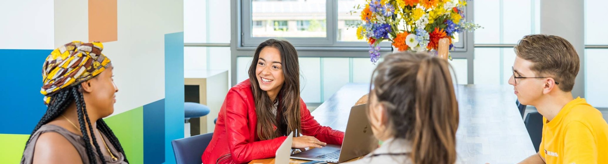 Lo-res. Groep van 4 studenten in overleg aan tafel in algemene ruimte HAN. 