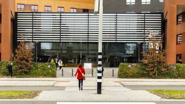 Een vrouwelijke studiekiezer loopt richting de hoofdingang van de Kapittelweg 33 om naar de Open Dag van HAN Social Work te gaan.