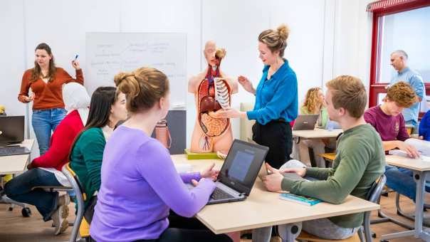 Meerdere studenten en docenten in leslokaal