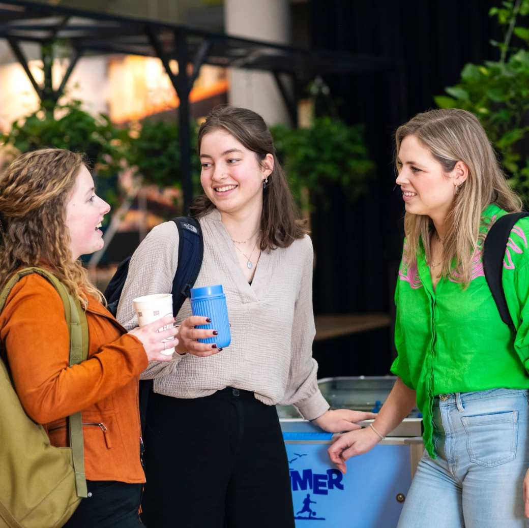 Drie studenten staan te kletsen in de kantine