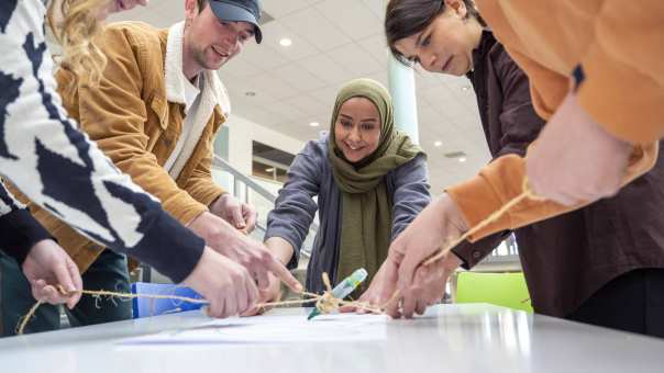 Groep studenten met een docent spelen een spel met een stift. (verzadiging en kleurbalans bewerkt)