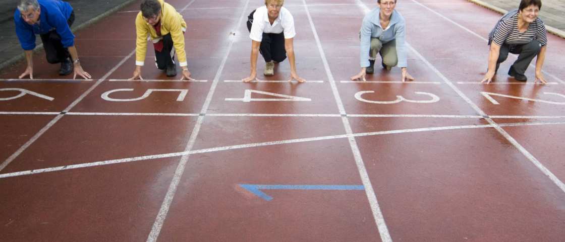 groepje actieve ouderen staat aan de startlijn van een hardloopbaan