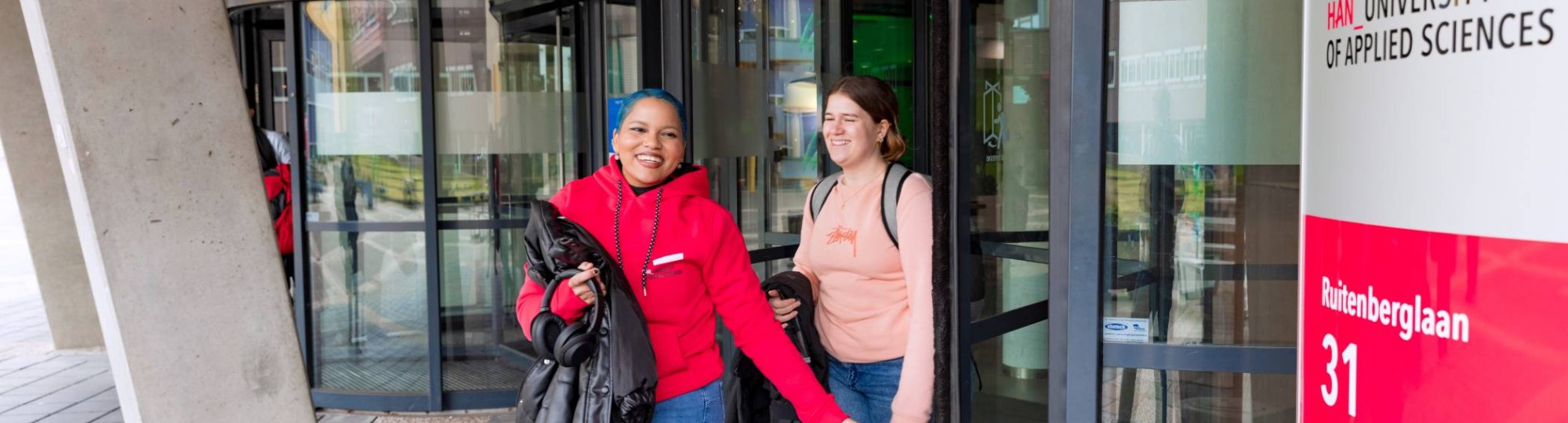 Noa and Chadionne walking through the entrance by Ruitenberglaan 31 HAN Arnhem campus.