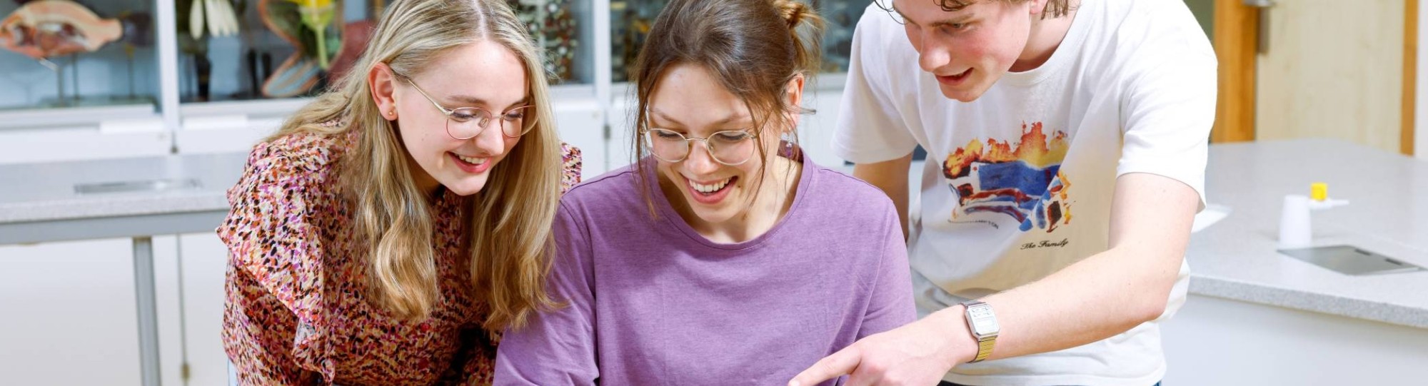 Drie studenten buigen zich samen over stenen en bekijken ze.