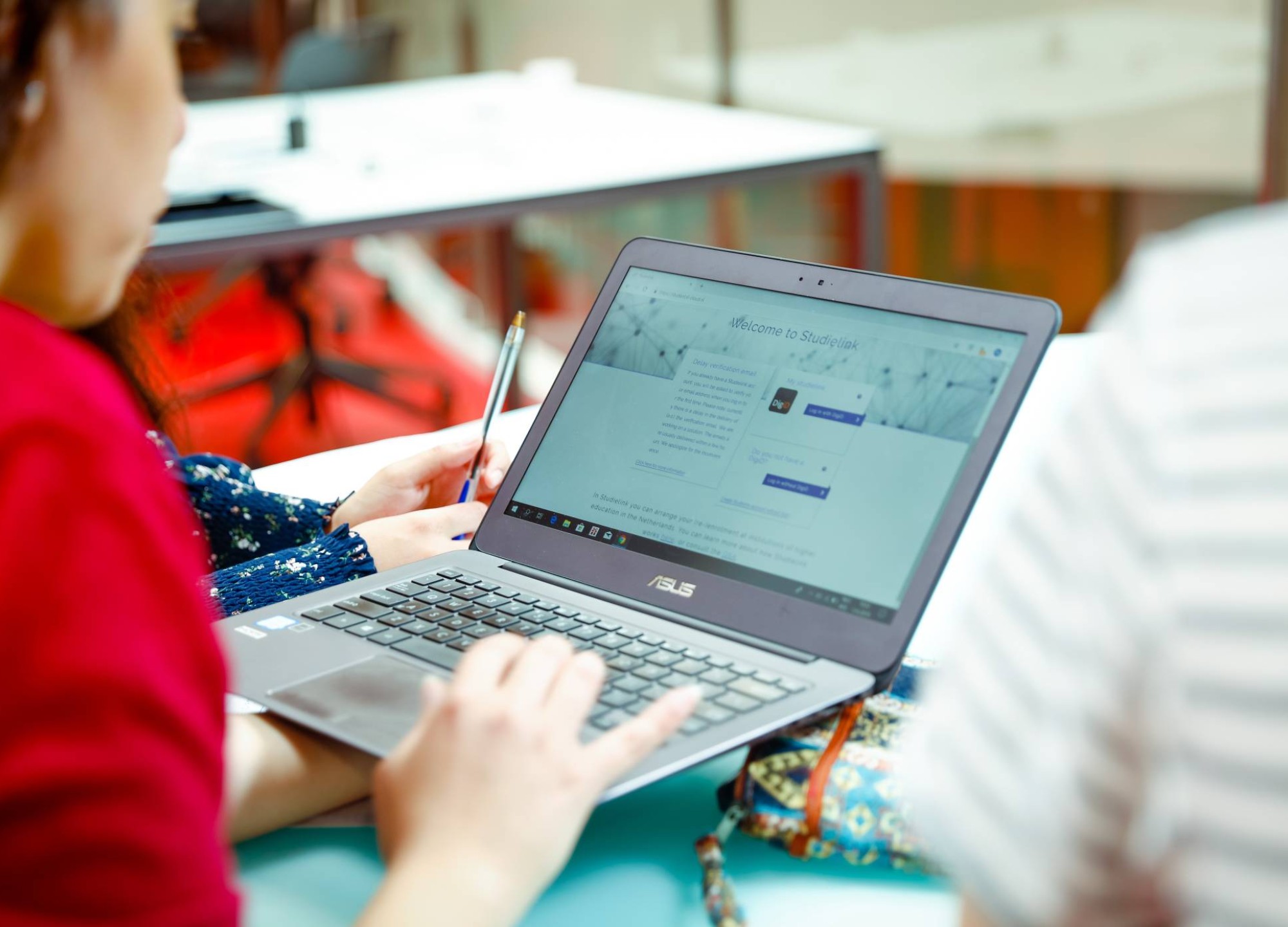 Een deeltijdstudent houdt een laptop vast met de Studielink pagina om zich aan te melden.