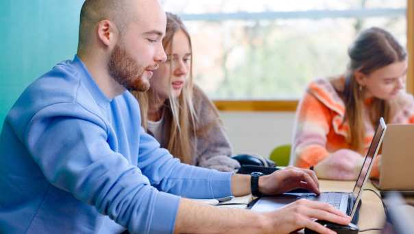 Deeltijd studenten zitten in lokaal en werken op een laptop