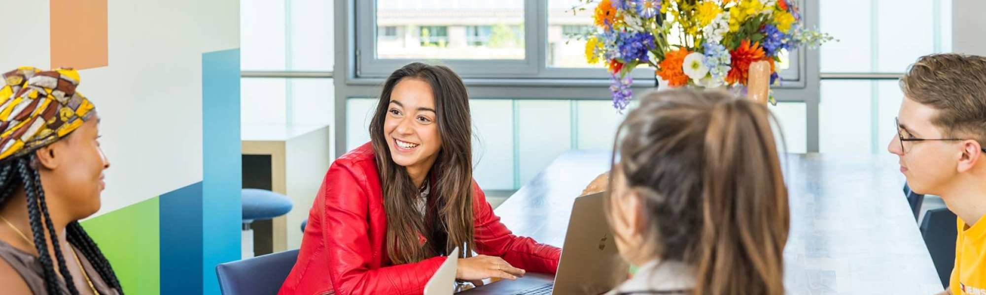 Lo-res. Groep van 4 studenten in overleg aan tafel in algemene ruimte HAN. 