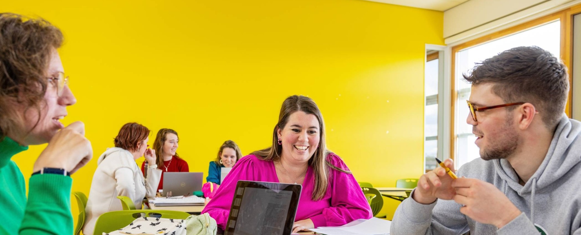 Twee studenten Leraar Nederlands bladeren door een boek in de mediatheek.