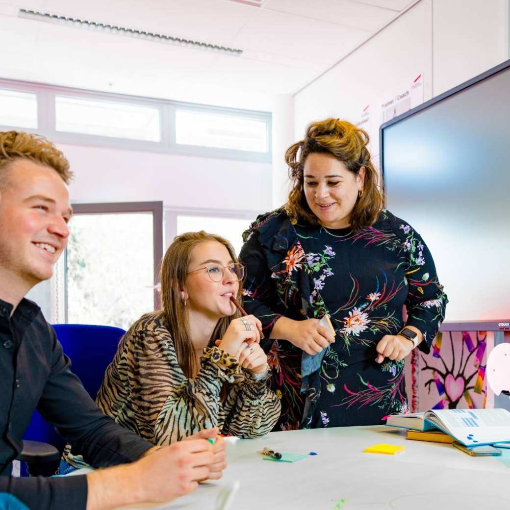 twee studenten van learning and development en een docent aan tafel